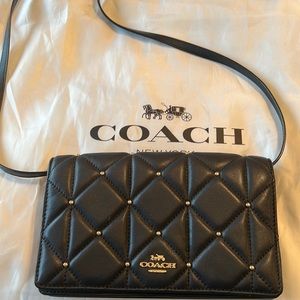 Small coach black crossbody with gold detail.